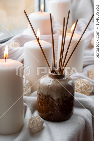 Aroma reed diffuser. Bottle container with wood stick diffusers Essential oils to scent your home fragnance concept autumn holidays at cozy home on the windowsill Hygge aesthetic atmosphere on knitted Aroma reed diffuser. Bottle container with wood stick diffusers Essential oils to scent your home fragnance concept autumn holidays at cozy home on the windowsill Hygge aesthetic atmosphere on knitted 104635953