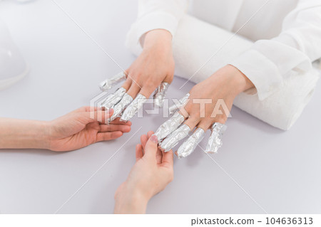Manicurist and Asian woman removing nails with acetone at nail salon Manicurist and Asian woman removing nails with acetone at nail salon 104636313