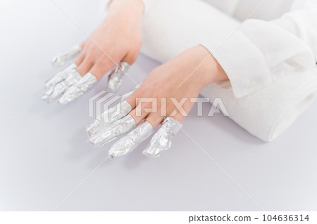 Manicurist and Asian woman removing nails with acetone at nail salon 104636314