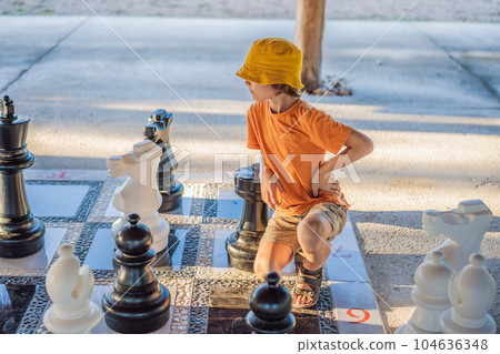 Father and son playing chess spending time together outdoor. Kid play chess 104636348