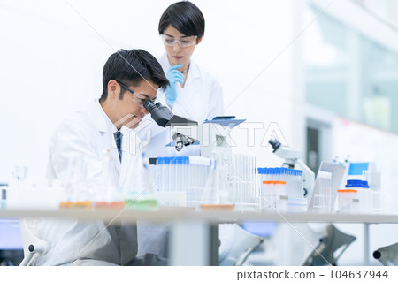 Researcher doing an experiment with a microscope in a laboratory Researcher doing an experiment with a microscope in a laboratory 104637944