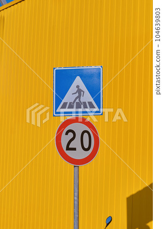 Vertical frame, traffic signs on against a bright yellow warehouse wall from a profiled metal wall, background ideas for a screen or design articles Vertical frame, traffic signs on against a bright yellow warehouse wall from a profiled metal wall, background ideas for a screen or design articles 104639803