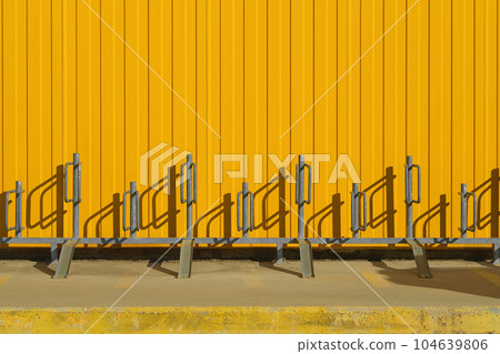 Bicycle parking near a bright yellow profiled metal wall, fence or warehouse idea, background for a screen or design articles 104639806