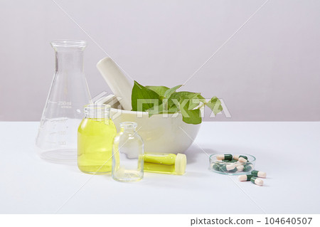 Some jars filled with essential oil arranged with a mortar of fish mint leaves and several green-white capsules. Research science content of Fish mint (Houttuynia cordata) Some jars filled with essential oil arranged with a mortar of fish mint leaves and several green-white capsules. Research science content of Fish mint (Houttuynia cordata) 104640507