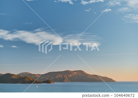 Beautiful sunset on the Aegean Sea with islands, mountains and a sailboat. Seascape, travel and vacation in nature, idea for a background or advertising sea voyages Beautiful sunset on the Aegean Sea with islands, mountains and a sailboat. Seascape, travel and vacation in nature, idea for a background or advertising sea voyages 104640672