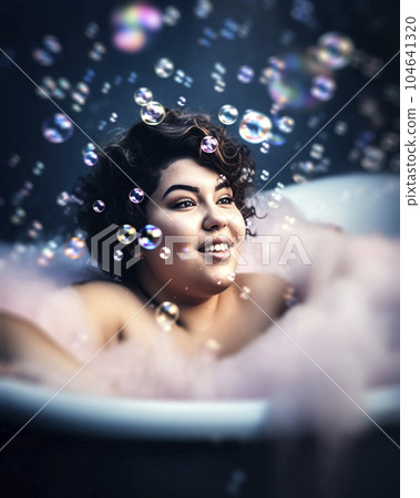 Young woman with black hair sits in a bubble bath with soap bubbles floating around her head, made with generative ai Young woman with black hair sits in a bubble bath with soap bubbles floating around her head, made with generative ai 104641320
