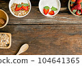Strawberry yogurt in a wooden bowl with granola, mint and fresh strawberry on wooden background. Health food concept 104641365