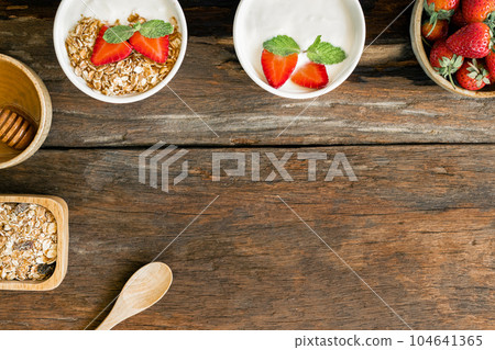 Strawberry yogurt in a wooden bowl with granola, mint and fresh strawberry on wooden background. Health food concept 104641365
