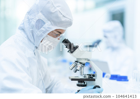研究人員在潔淨室中使用顯微鏡進行實驗 104641413