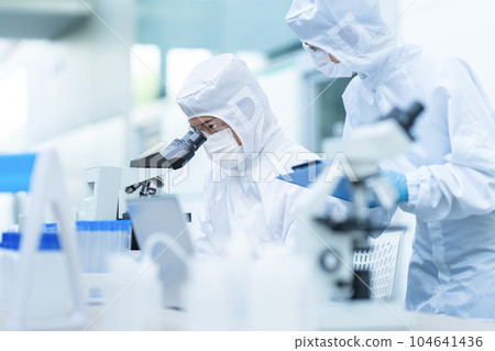 A researcher conducting an experiment in a clean room 104641436