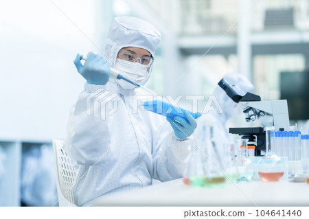 A researcher conducting an experiment in a clean room A researcher conducting an experiment in a clean room 104641440