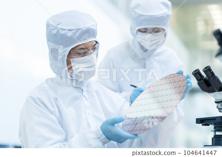 Engineer inspecting wafers in clean room 104641447