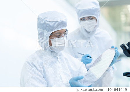 Engineer inspecting wafers in clean room 104641449
