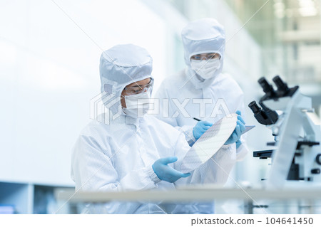Engineer inspecting wafers in clean room 104641450