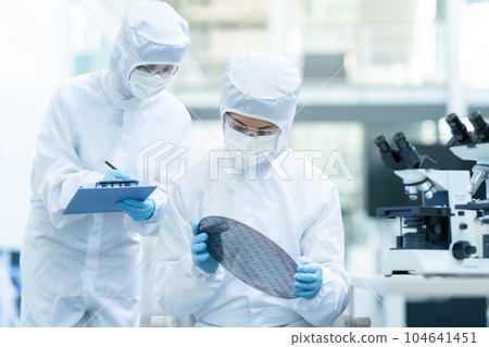 Engineer inspecting wafers in clean room Engineer inspecting wafers in clean room 104641451