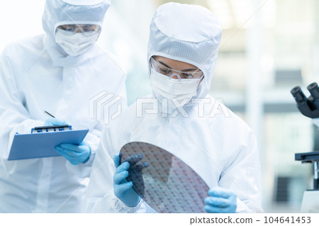 Engineer inspecting wafers in clean room 104641453