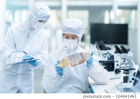 Engineer inspecting wafers in clean room 104641461