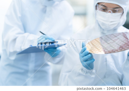 Engineer inspecting wafers in clean room 104641463
