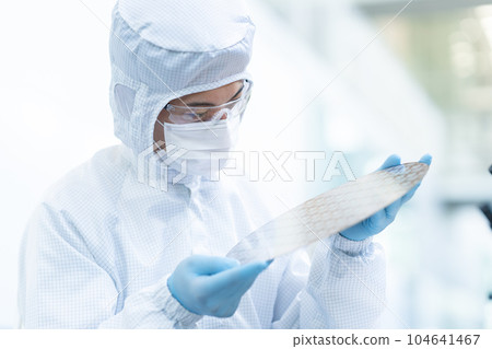 Engineer inspecting wafers in clean room 104641467