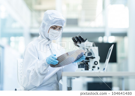 Engineer inspecting wafers in clean room 104641480
