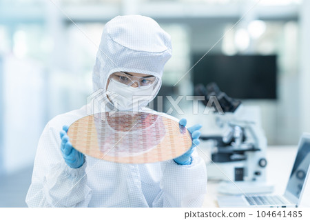 Engineer inspecting wafers in clean room Engineer inspecting wafers in clean room 104641485