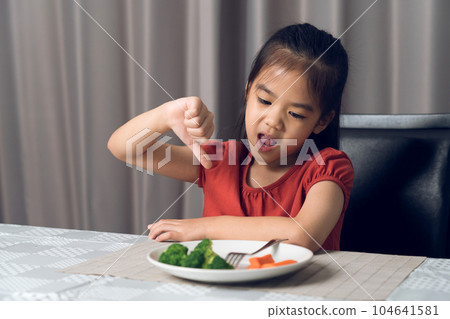 Little cute kid girl refusing to eat healthy vegetables. Children do not like to eat vegetables. Little cute kid girl refusing to eat healthy vegetables. Children do not like to eat vegetables. 104641581