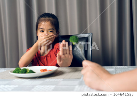 Little cute kid girl refusing to eat healthy vegetables. Children do not like to eat vegetables. Little cute kid girl refusing to eat healthy vegetables. Children do not like to eat vegetables. 104641583