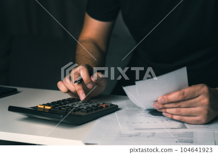 Asian man using calculator to calculate expenses while holding family bills at his home. 104641923
