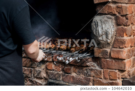 a man cooks kebab outdoor. 104642010