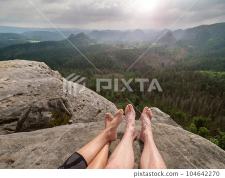 Bare feet hikers resting on summit after long hiking day. Bare feet hikers resting on summit after long hiking day. 104642270