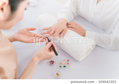 Manicurist and Asian woman discussing design options at nail salon Manicurist and Asian woman discussing design options at nail salon 104642301