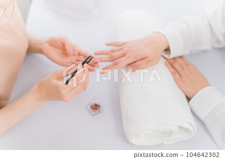 Manicurist and Asian woman discussing design options at nail salon 104642302