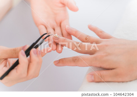 Manicurist and Asian woman discussing design options at nail salon 104642304