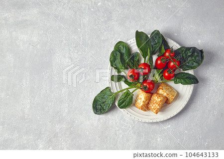 Red cherry tomatoes on a branch, green spinach leaves and fried 104643133