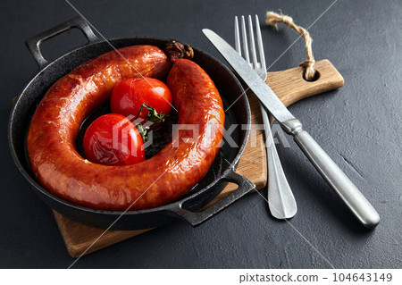 fried meat sausage in a cast iron skillet with tomatoes and cutl fried meat sausage in a cast iron skillet with tomatoes and cutl 104643149