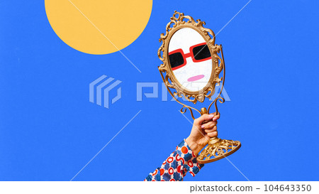 Female hand holding small mirror with drawn facial expression over blue background. Doodles, sketches, cartoon drawing style Female hand holding small mirror with drawn facial expression over blue background. Doodles, sketches, cartoon drawing style 104643350