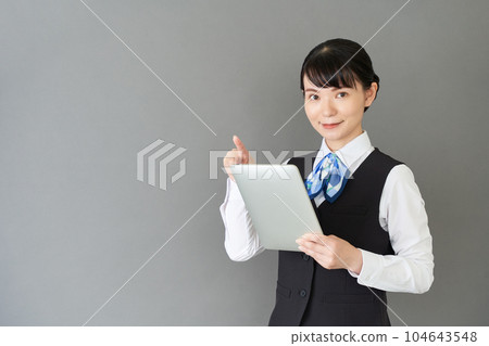 A woman in reception and clerical work wearing a ribbon tie uniform on a tablet operating vest A woman in reception and clerical work wearing a ribbon tie uniform on a tablet operating vest 104643548