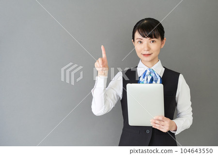A woman in reception and clerical work wearing a ribbon tie uniform on a tablet operating vest 104643550