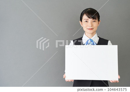 一位從事接待工作和文書工作的女性，穿著絲帶領帶制服，背心上有白板 104643575