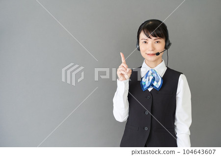 A woman in reception work and clerical work wearing a uniform with a ribbon tie on a vest wearing a headset A woman in reception work and clerical work wearing a uniform with a ribbon tie on a vest wearing a headset 104643607