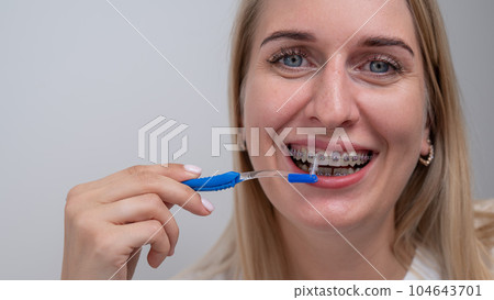 Caucasian woman cleaning her teeth with braces using a brush.  104643701