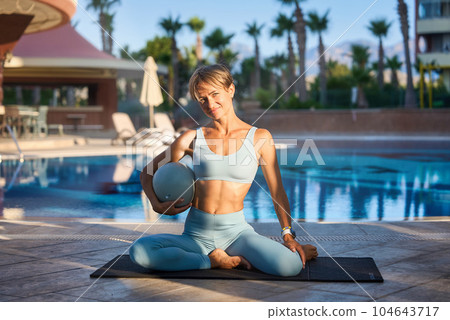 Caucasian girl doing pilates with special equipment outdoor. Workout, yoga, balance, concentration 104643717