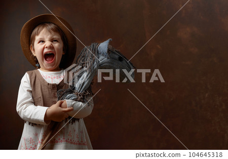 Screaming little girl with a homemade toy. Screaming little girl with a homemade toy. 104645318