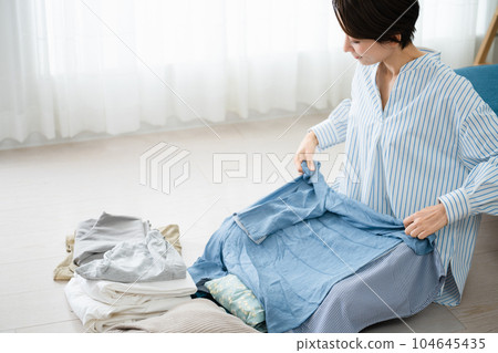 Young woman folding laundry Lifestyle image Young woman folding laundry Lifestyle image 104645435