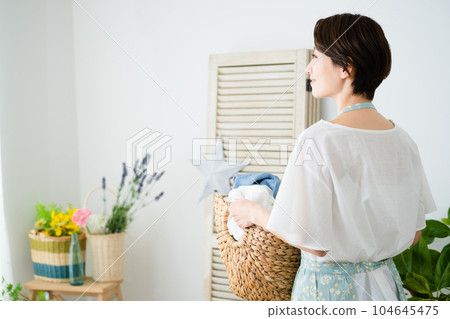 Young woman holding a laundry basket Lifestyle image Young woman holding a laundry basket Lifestyle image 104645475