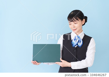 一名從事接待工作和文書工作的女性,身穿制服,背心上繫著絲帶,背心上有黑板 一名從事接待工作和文書工作的女性,身穿制服,背心上繫著絲帶,背心上有黑板 104646267