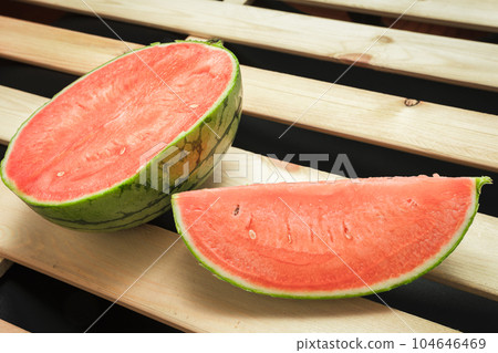 The watermelon placed on a wooden board. 104646469