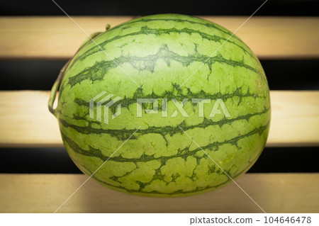 The watermelon placed on a wooden board. 104646478