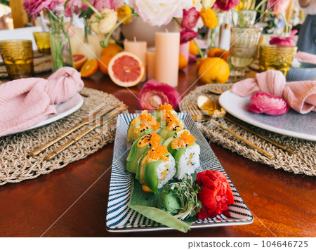 Green dragon rolls lie on a bamboo leaf on a rectangular dish on the table 104646725