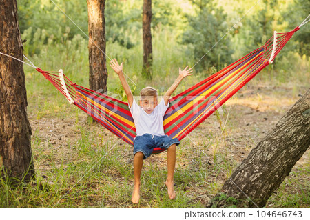 Cute little blond caucasian boy having fun with multicolored hammock Cute little blond caucasian boy having fun with multicolored hammock 104646743